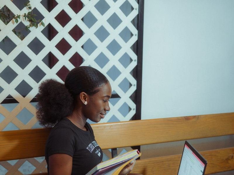 Une jeune femme qui étudie avec un cahier et un ordinateur