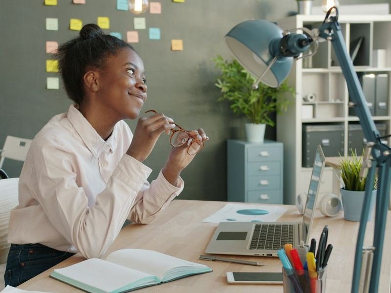Une femme souriante à son bureau, dans un grand open space